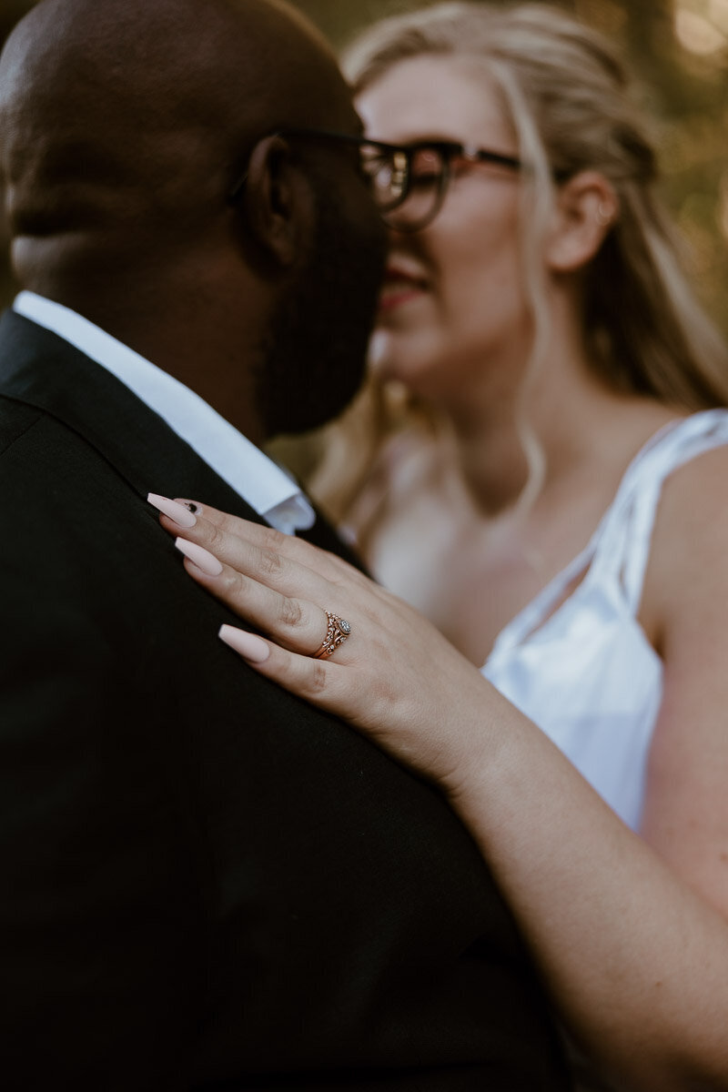 Detail shot of a bride's rings while kissing her groom