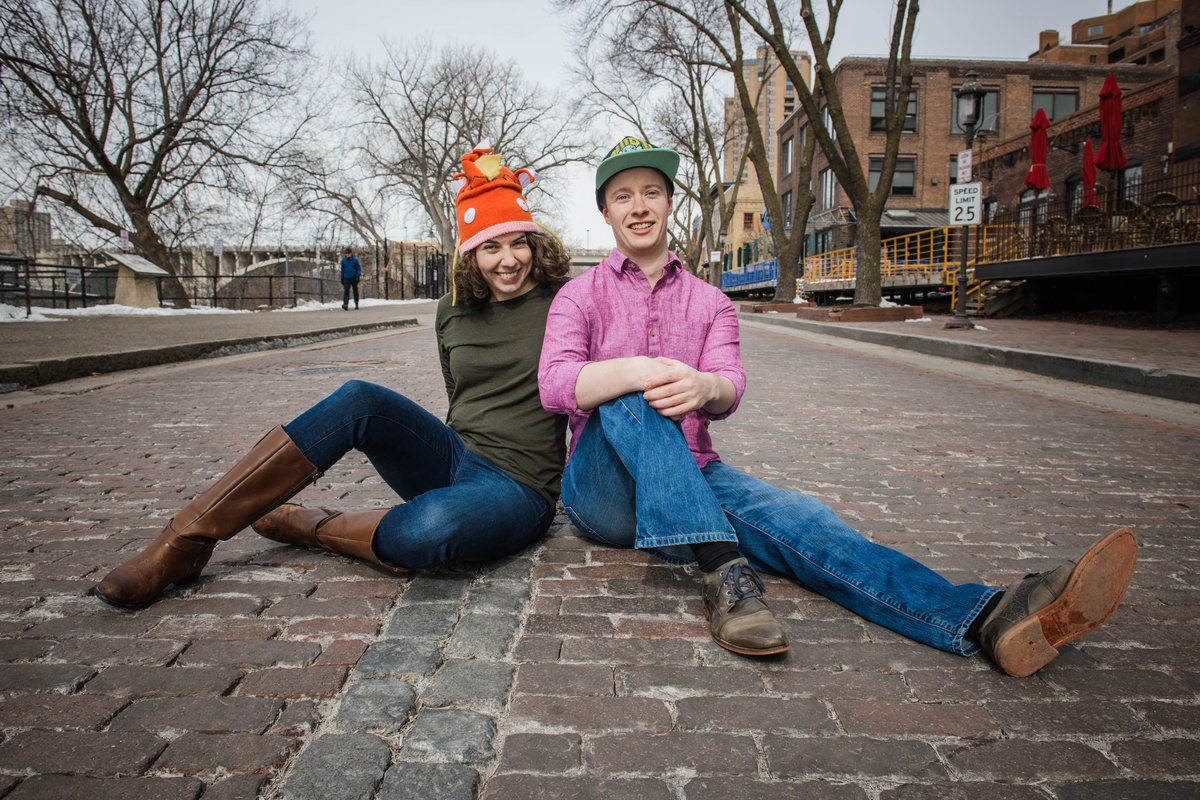 Man and woman smile and sit on the cobblestone in Minneapolis, Minnesota.