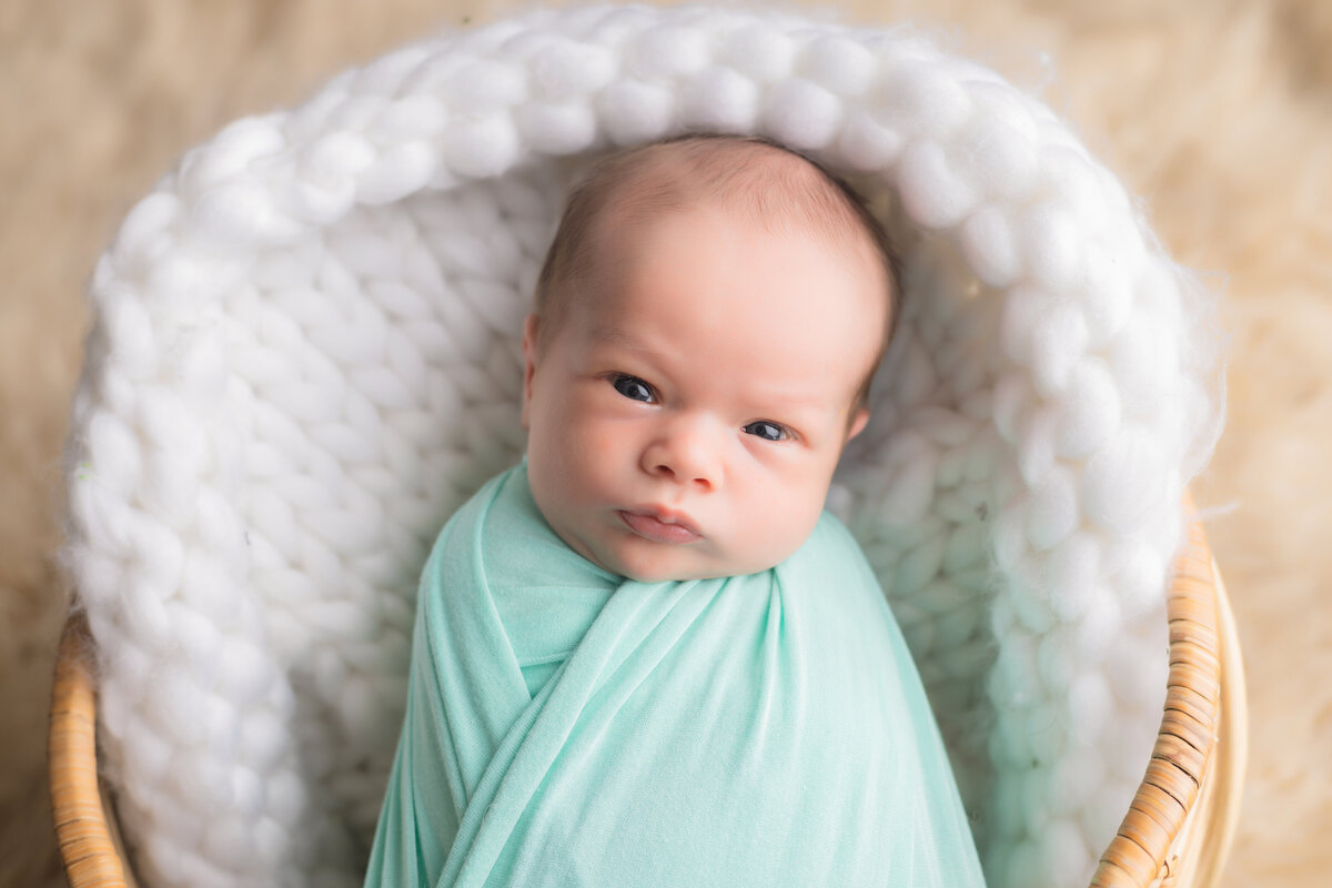 Newborn Photographer, a baby is awake swaddled in a basket