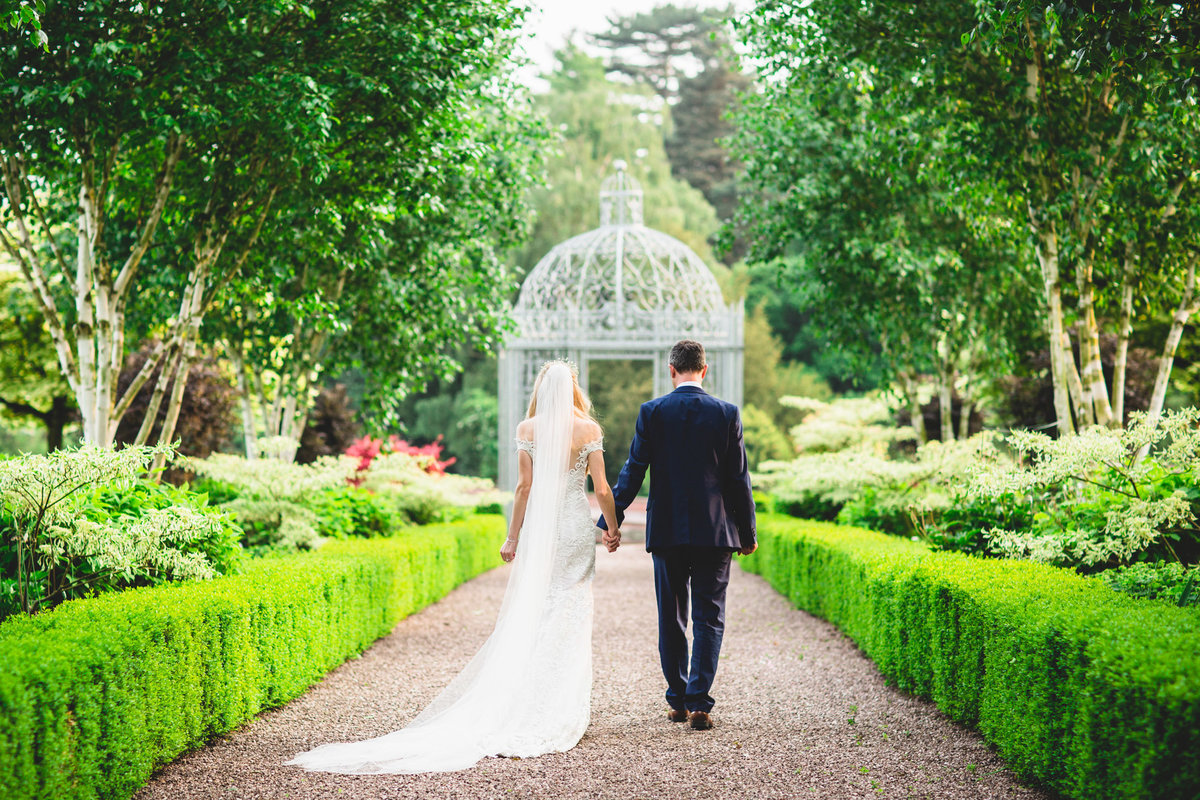 bride and groom walking through the gardens at capesthorne hall