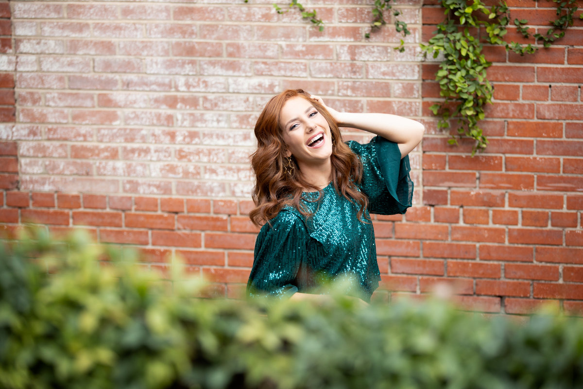 Girl smiling wearing a green sequins top and red hair