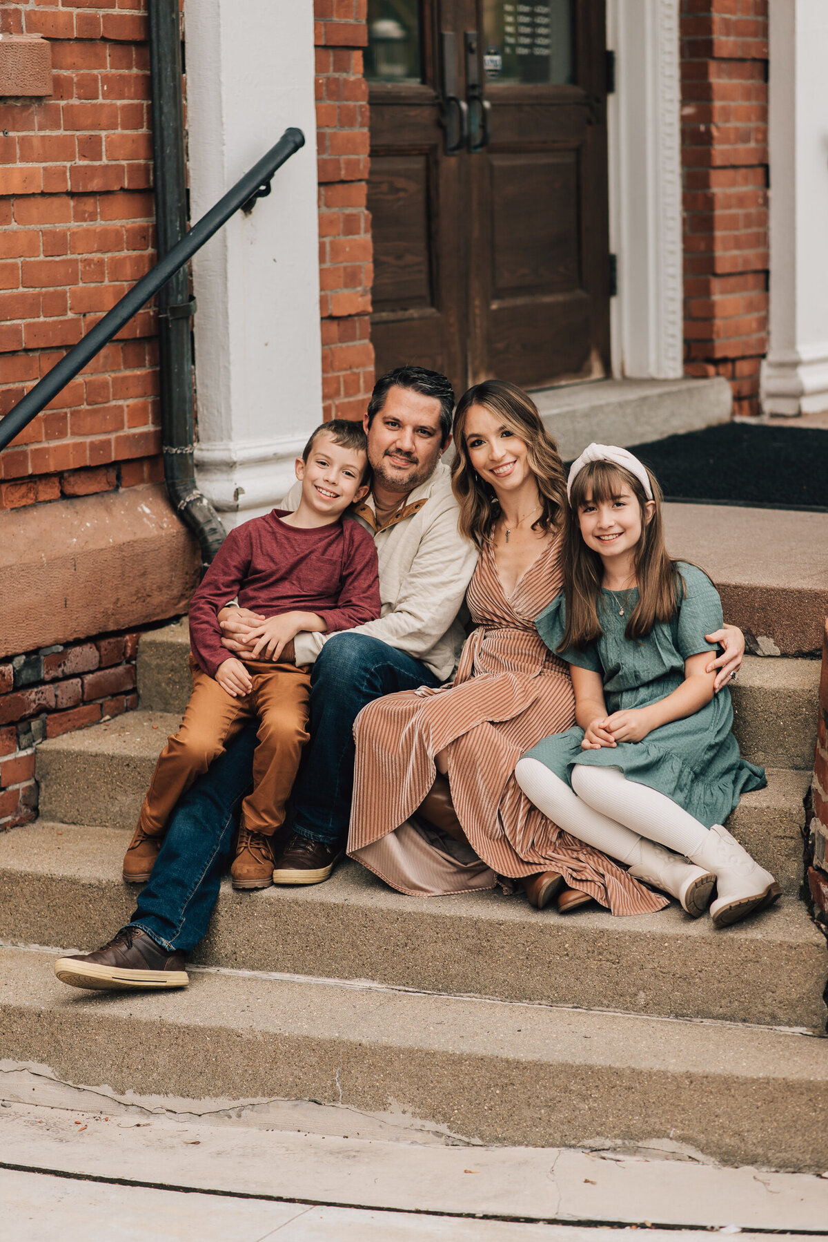 A mom, dad and their two kids, smiling from a set of stairs at their family photo shoot in Canton, Connecticut.
