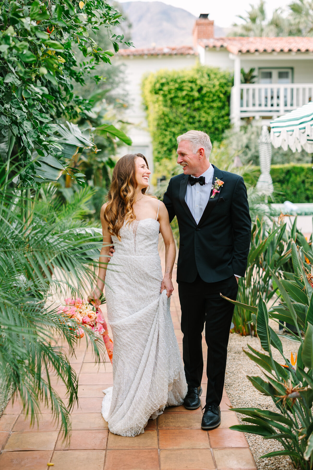 bride and groom standing side by side smiling at each other with green trees and landscaping surrounding them at napa wedding venue.