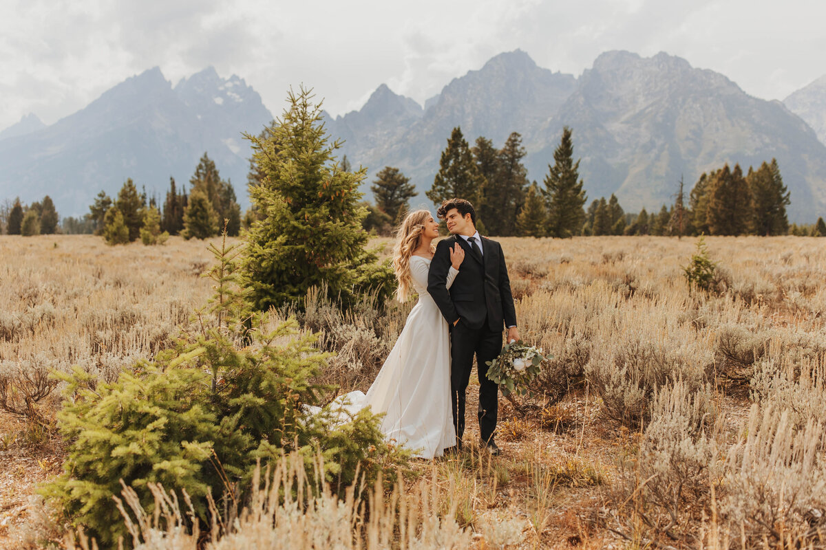 bride and groom embracing by mountains