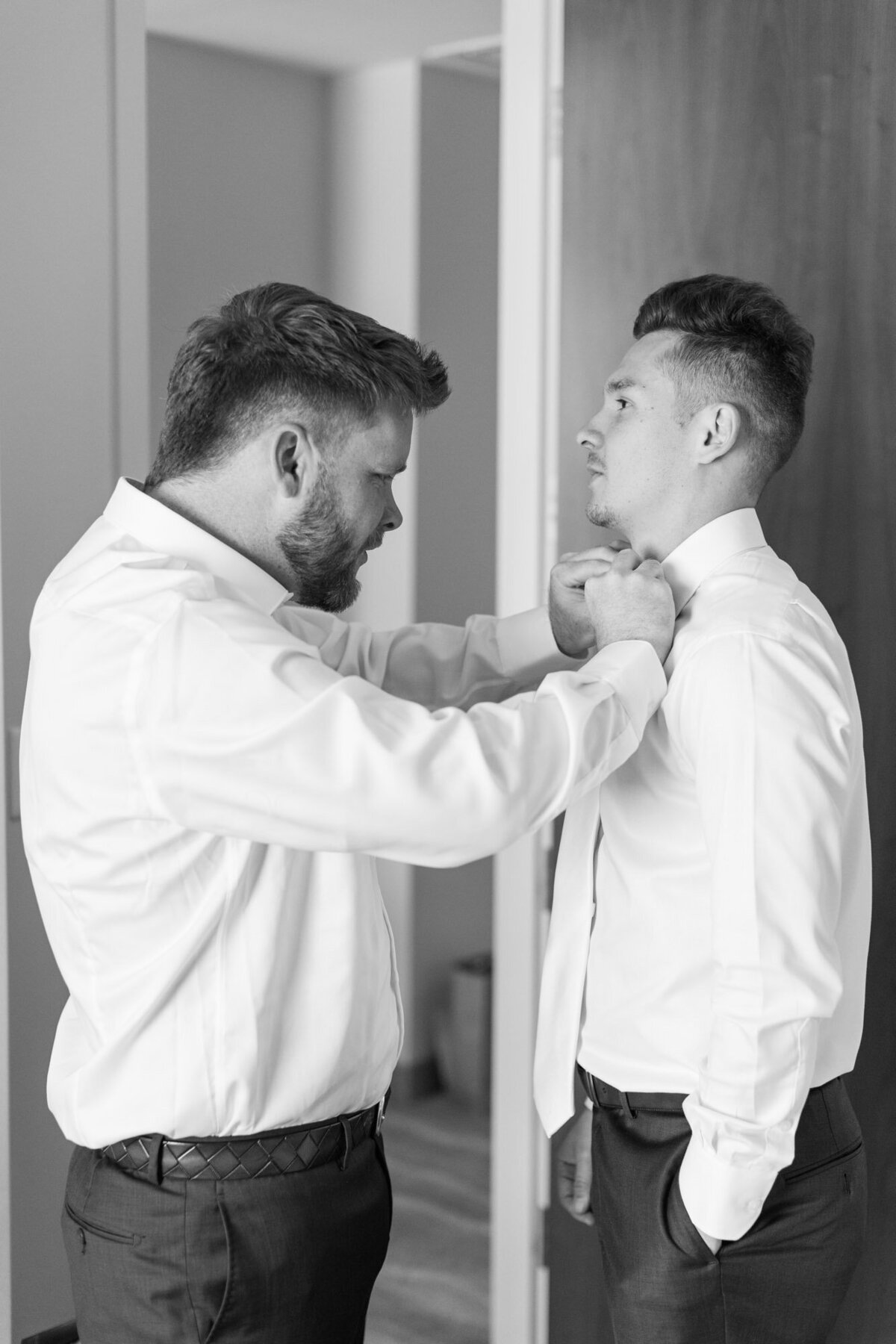 man helping groom with his tie