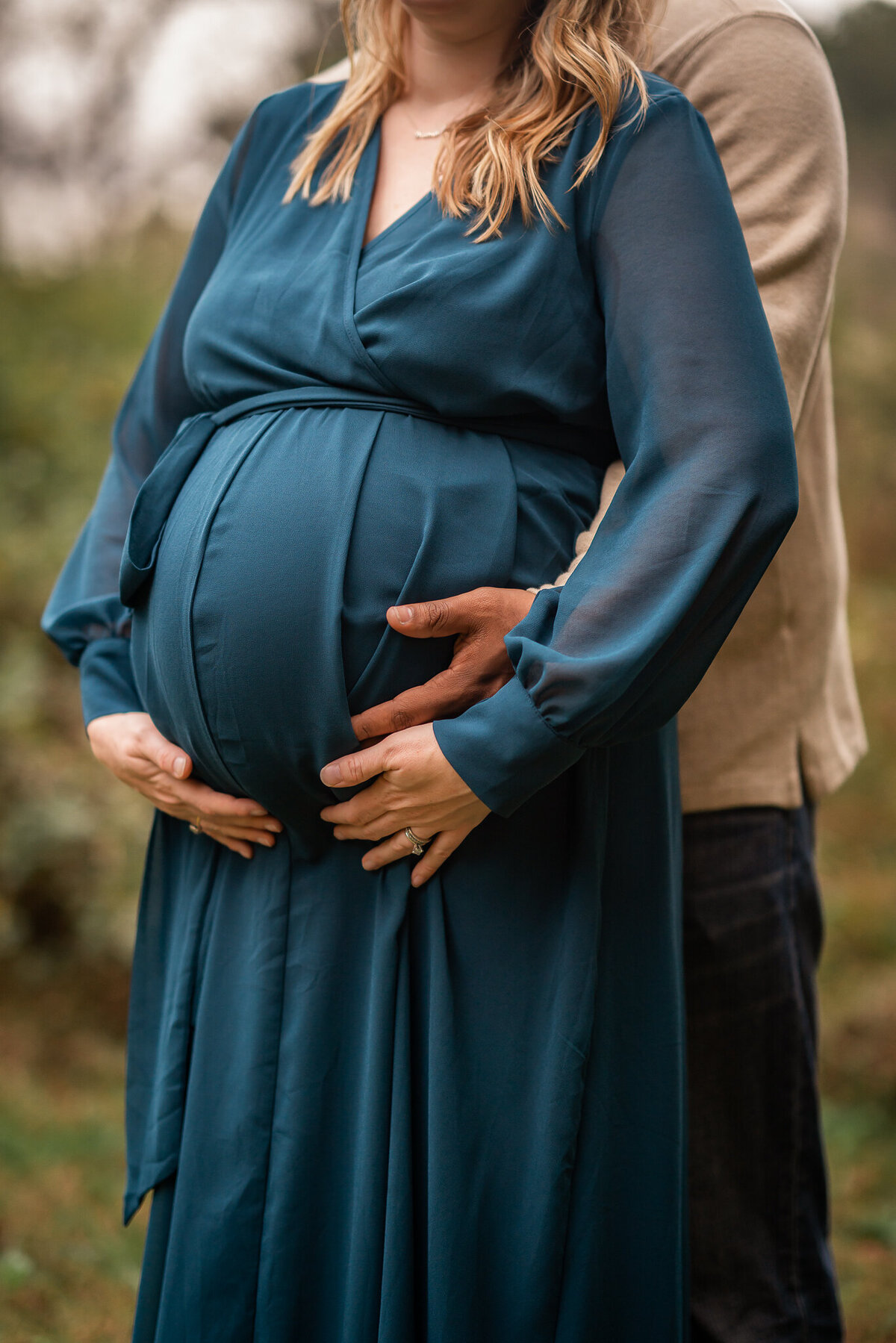A dad is cradling his pregnant wife's belly in their maternity pictures in Newnan, GA.