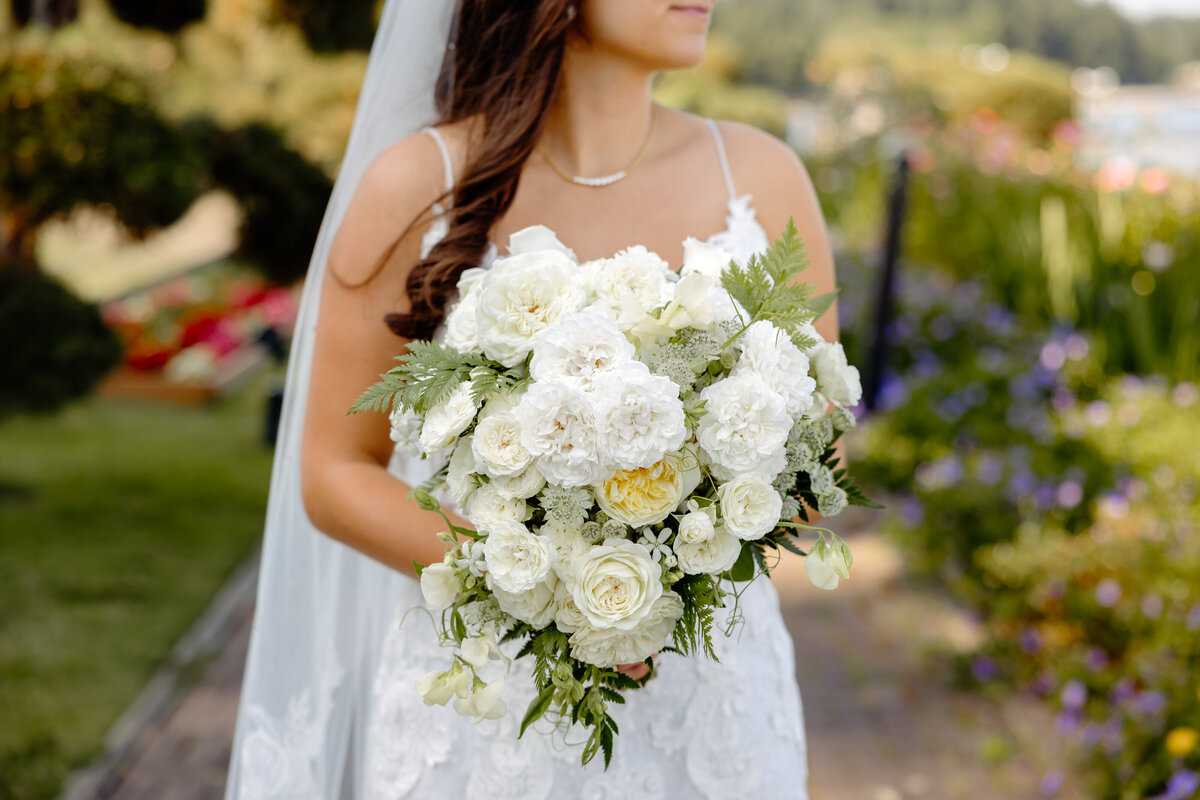 bride holds her white and green bouquet for  portraits at kiana lodge
