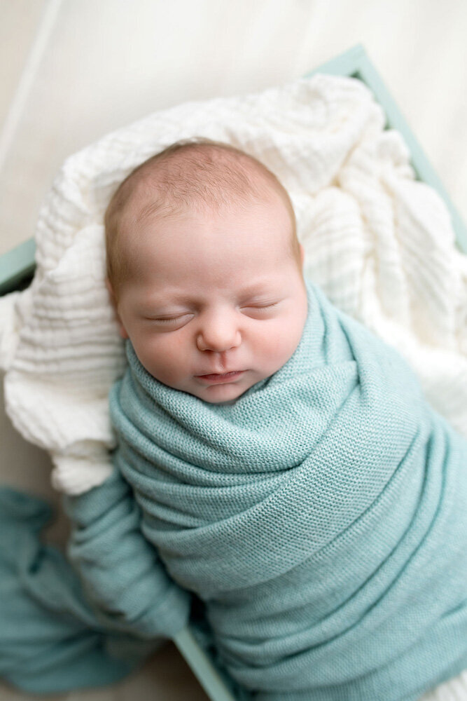 Newborn session of baby boy wearing a blue blanket