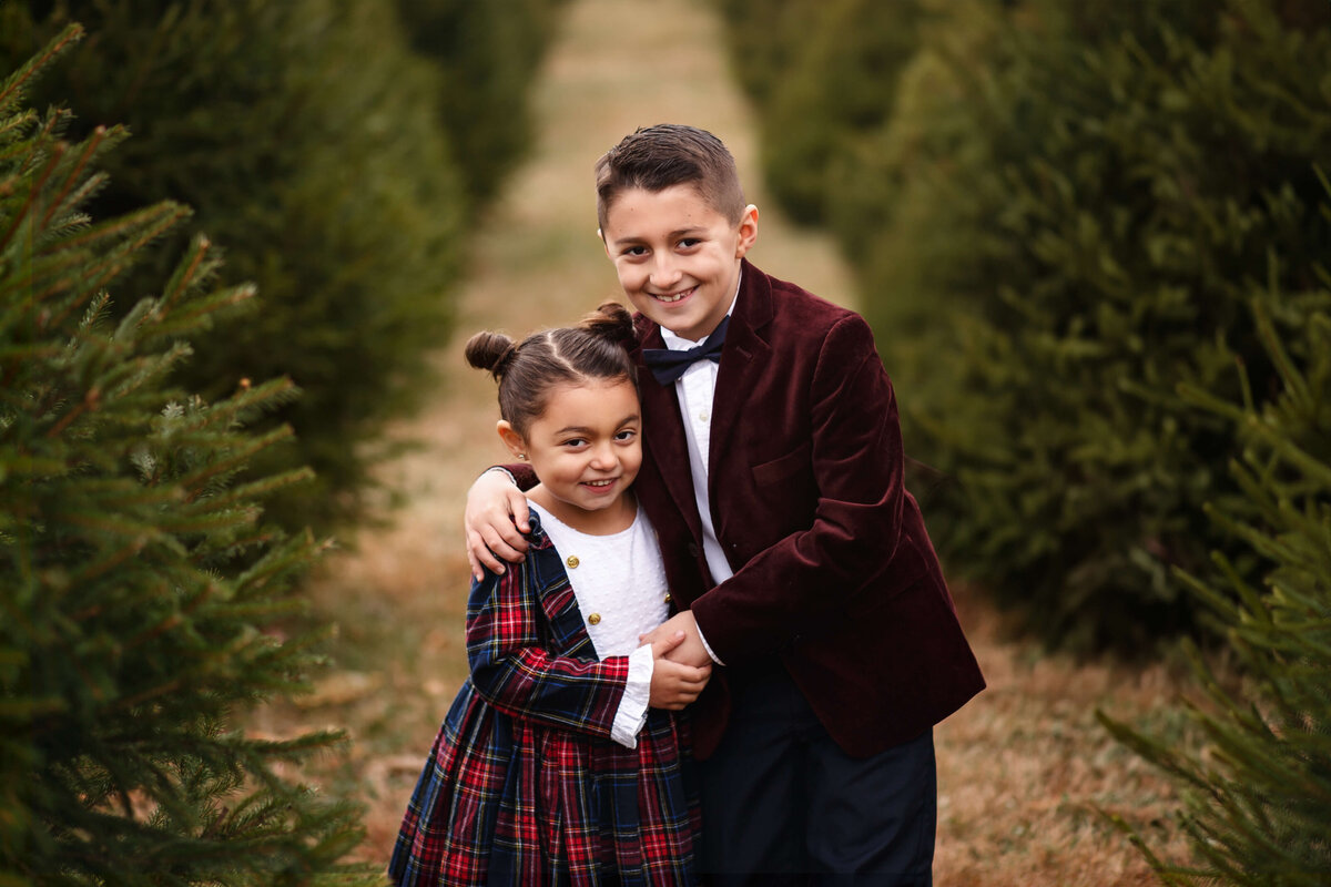 brother and sister at a christmas tree farm a a holiday christmas family photography session