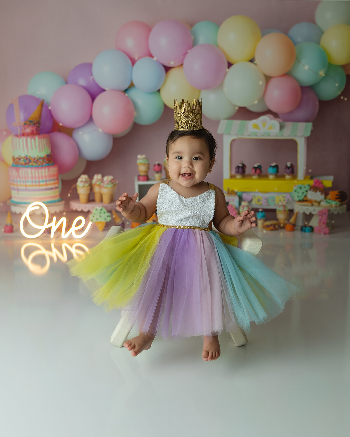 A young toddler girl plays in a colorful tule dress for her first birthday in a New Jersey Milestone Photographer studio