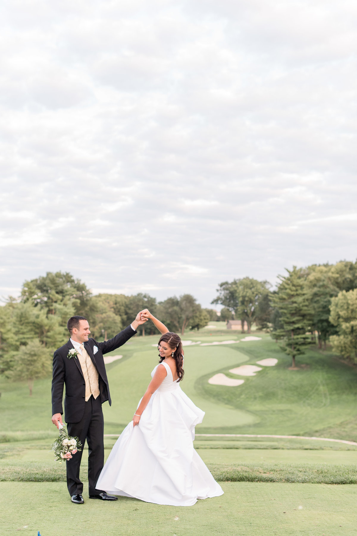 Groom twirling his Bride under left arm on golf green at Lancaster Country Club.