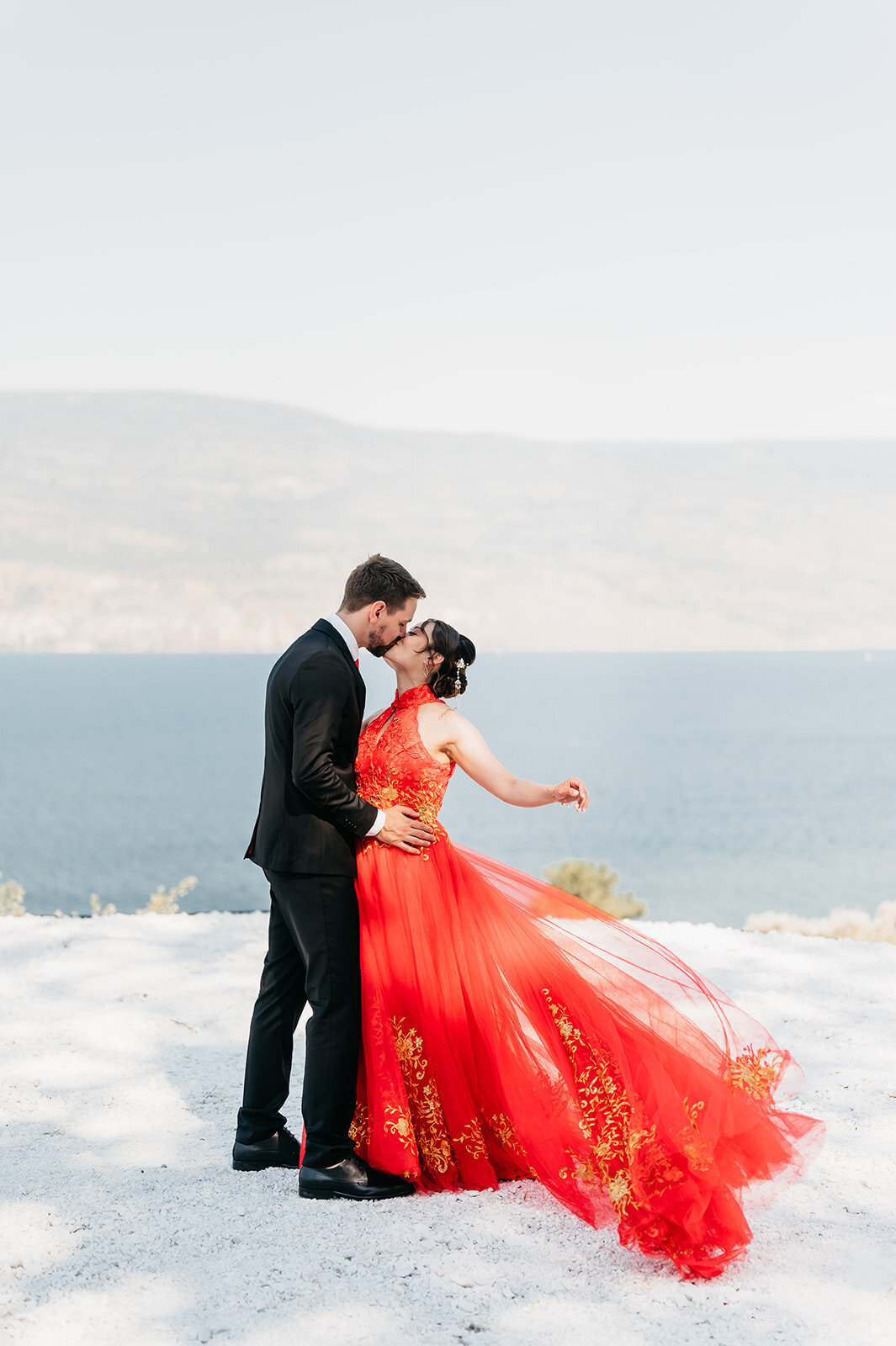 Modern red bridal dress with groom in a black suit on their wedding day.