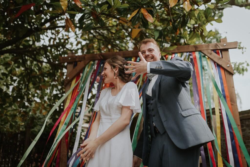 Groom showing off wedding ring in front of ceremony streamers