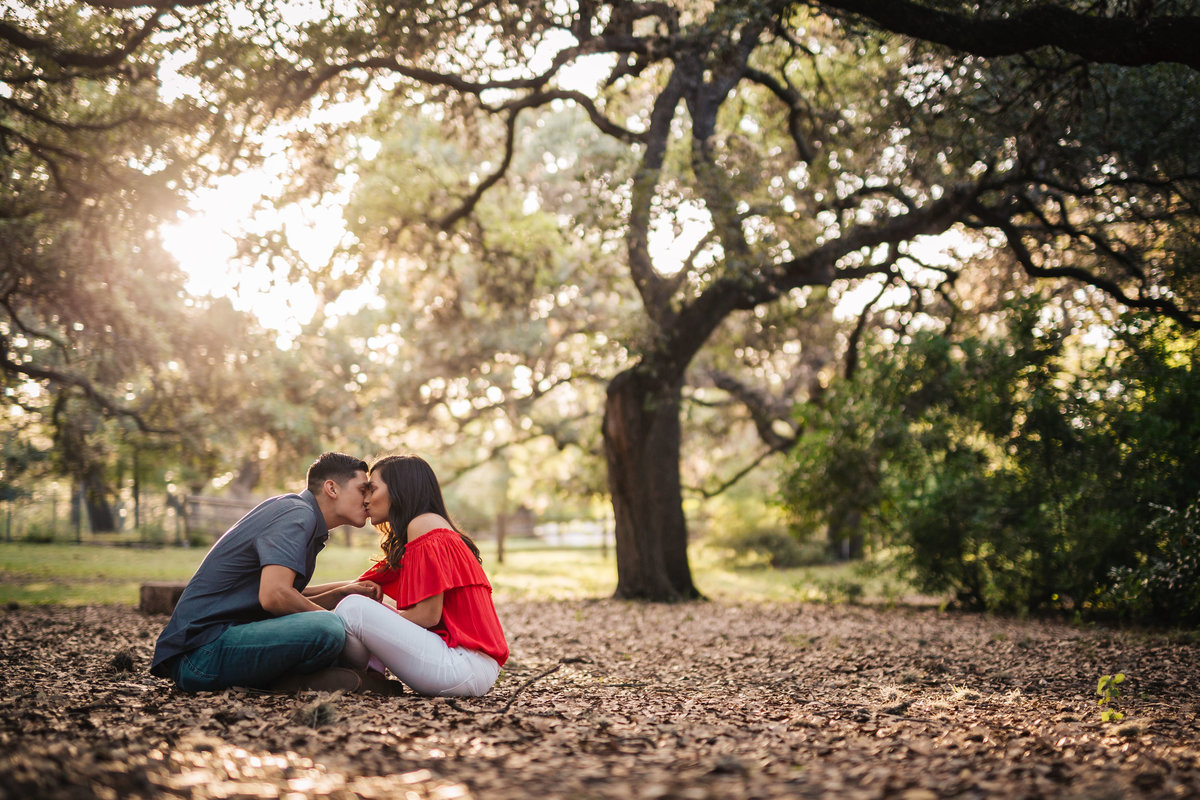 Couple kissing sitting on leaves for family photography session by San Antonio Photographer Expose The Heart Photography