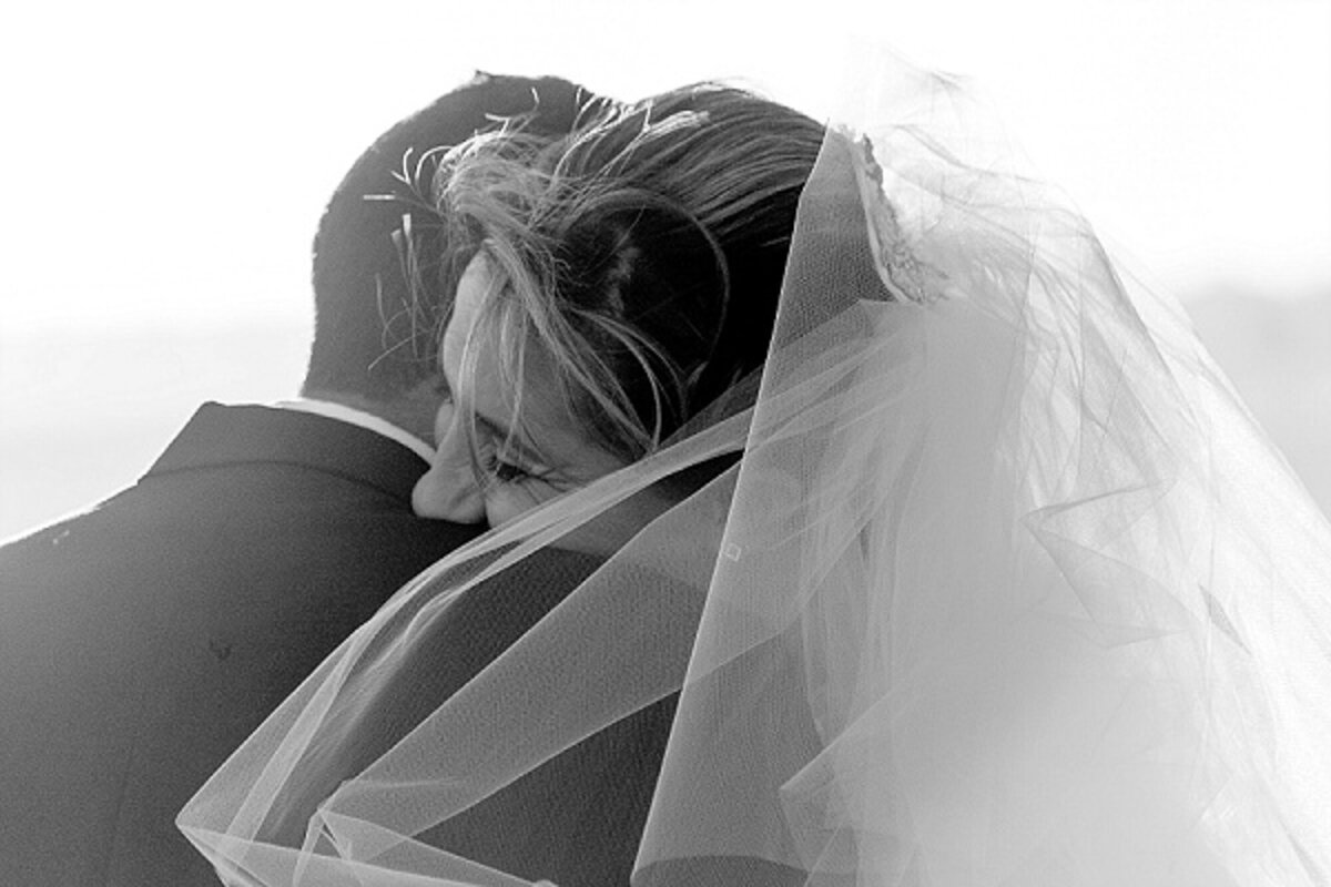 Black and white photograph of an emotional embrace between bride and groom after their ceremony