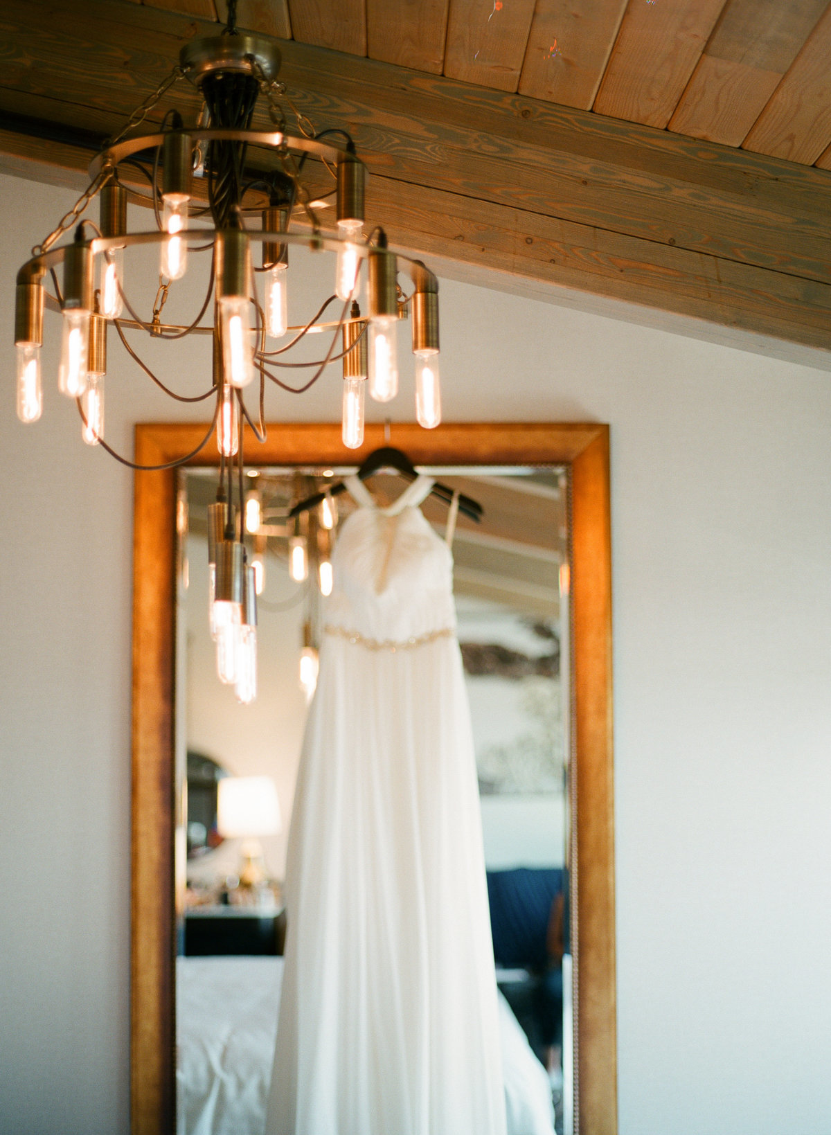 wedding day details dress hanging on mirror in charmant hotel edison bulb chandellier