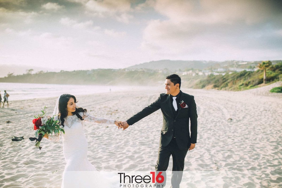 Bride and Groom hold hands on the beach during the photo session