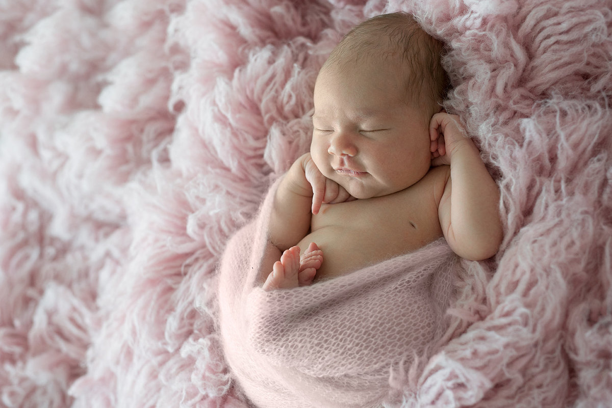 a newborn baby girl wrapped in pink