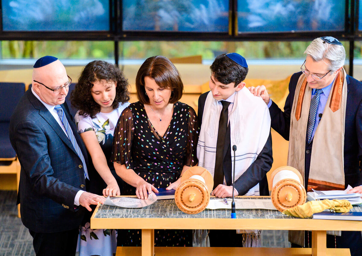 An image of some Bellevue Bar and Bat Mitzvah Photography of a family reading from the torah together at the bimah with a rabbi