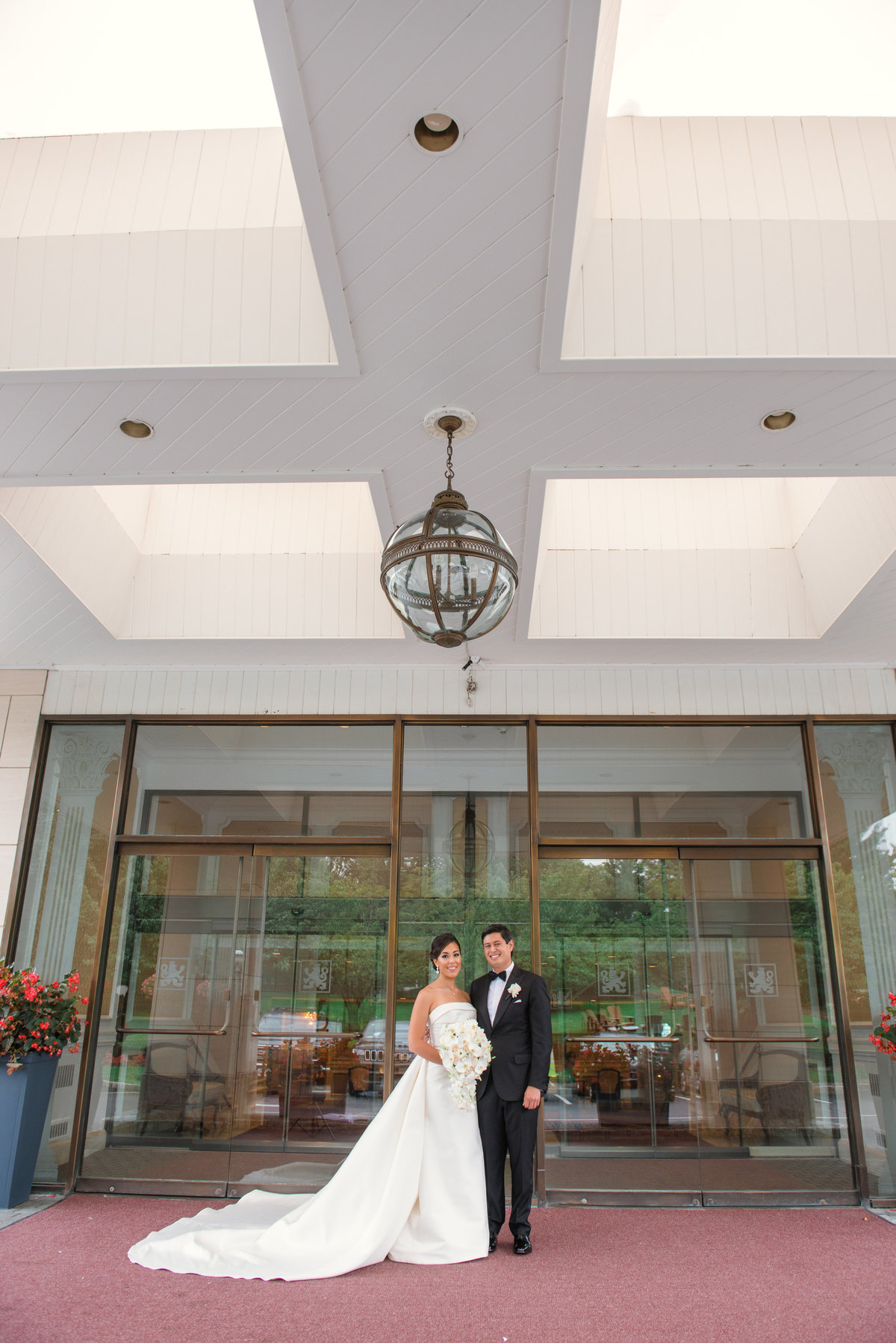 wedding photo of bride and groom standing at the front entrance of The Garden City Hotel
