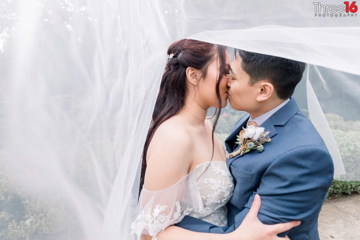 Bride and Groom share a kiss under her flowing veil