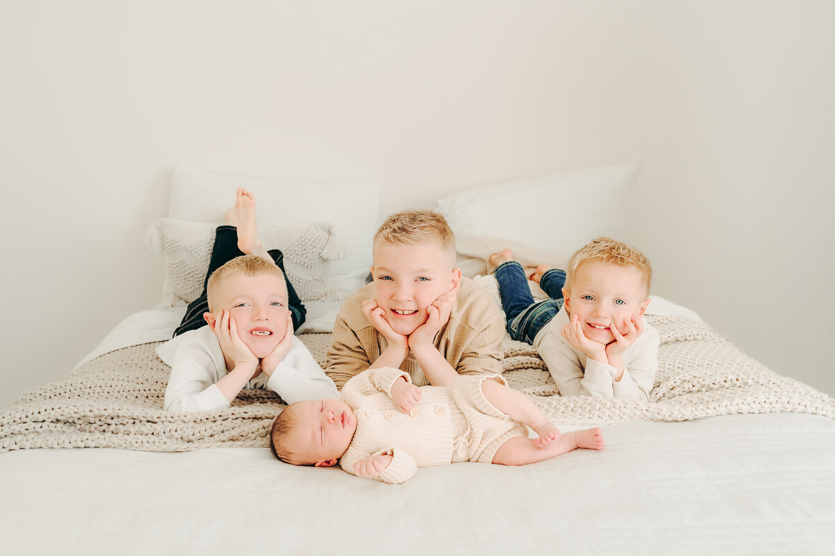 brothers pose for photo on bed with their newborn brother in jackson missouri
