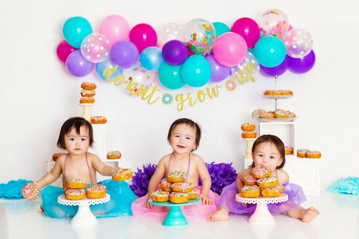 Cake Smash Photographer, three babies sit before plates full of donuts