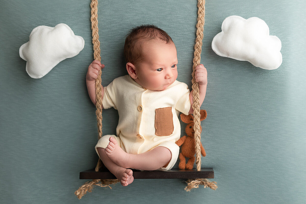 Baby boy posed on a swing prop during his newborn session.