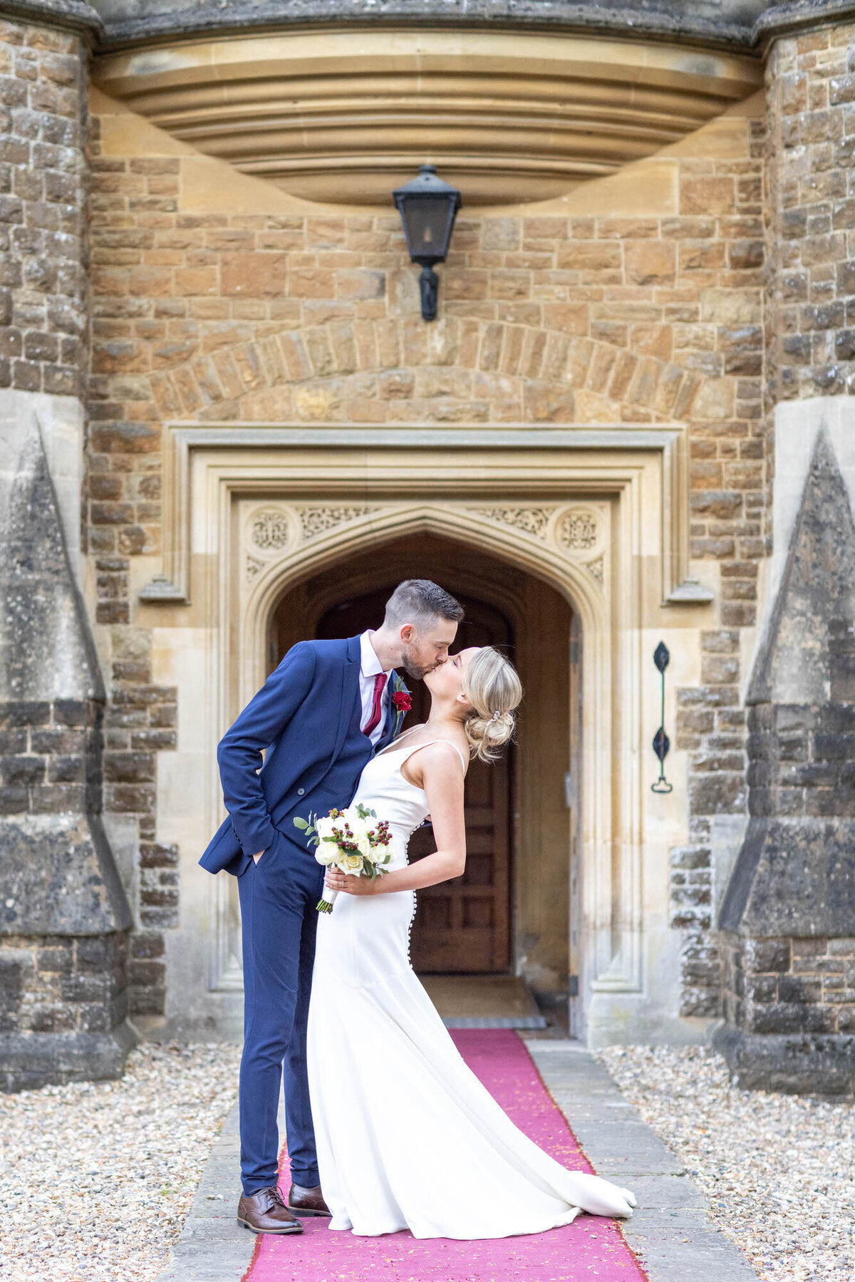 Groom Kissing Bride in front of english church arch