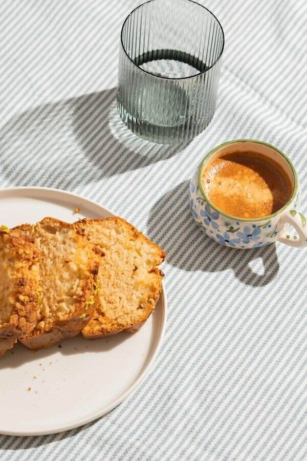 Espresso, pistachio cake, and water on a striped table — symbolizing balance and virtual non diet nutrition counseling.