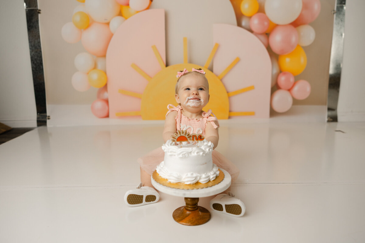 Adorable little one enjoying her cake smash moment under a pastel sunrise, complete with frosting fun and sunshine smiles. Captured by Yucaipa cake smash photographer Kaitlyn Dawn Photography.
