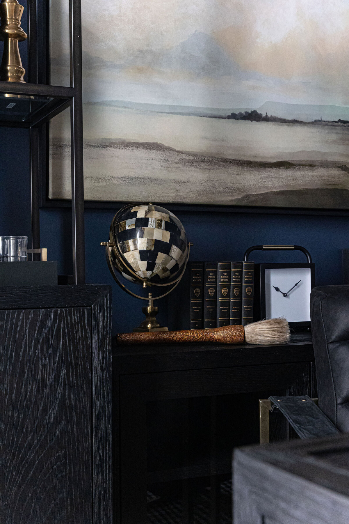 a globe, books, and a clock on a shelf in an office