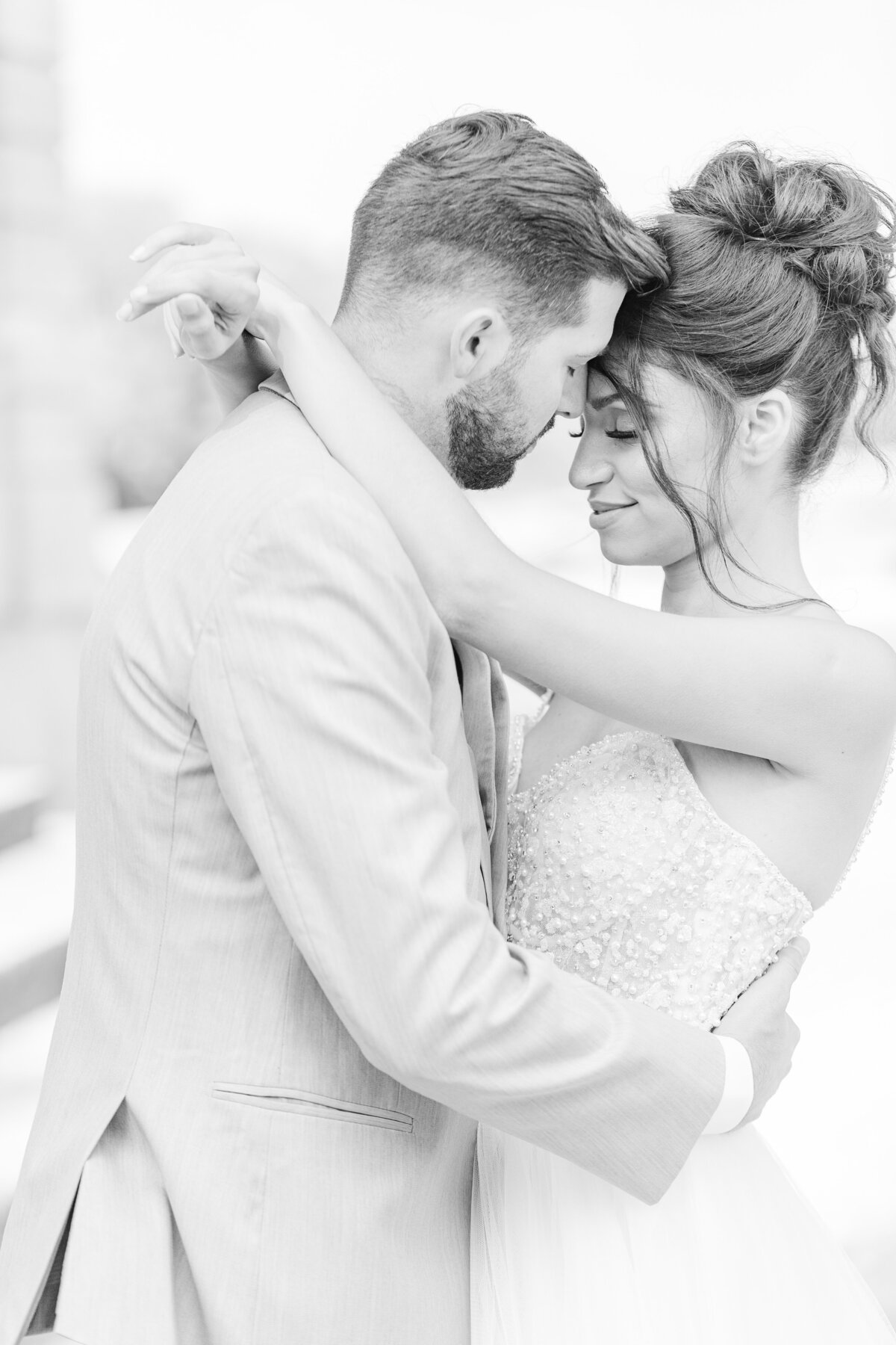 Black and white image. A bride and groom are touching heads with their eyes closed. The bride's arms are draped around the groom's neck. Intimate wedding photo captured by premier North Shore wedding photographer Lia Rose Weddings