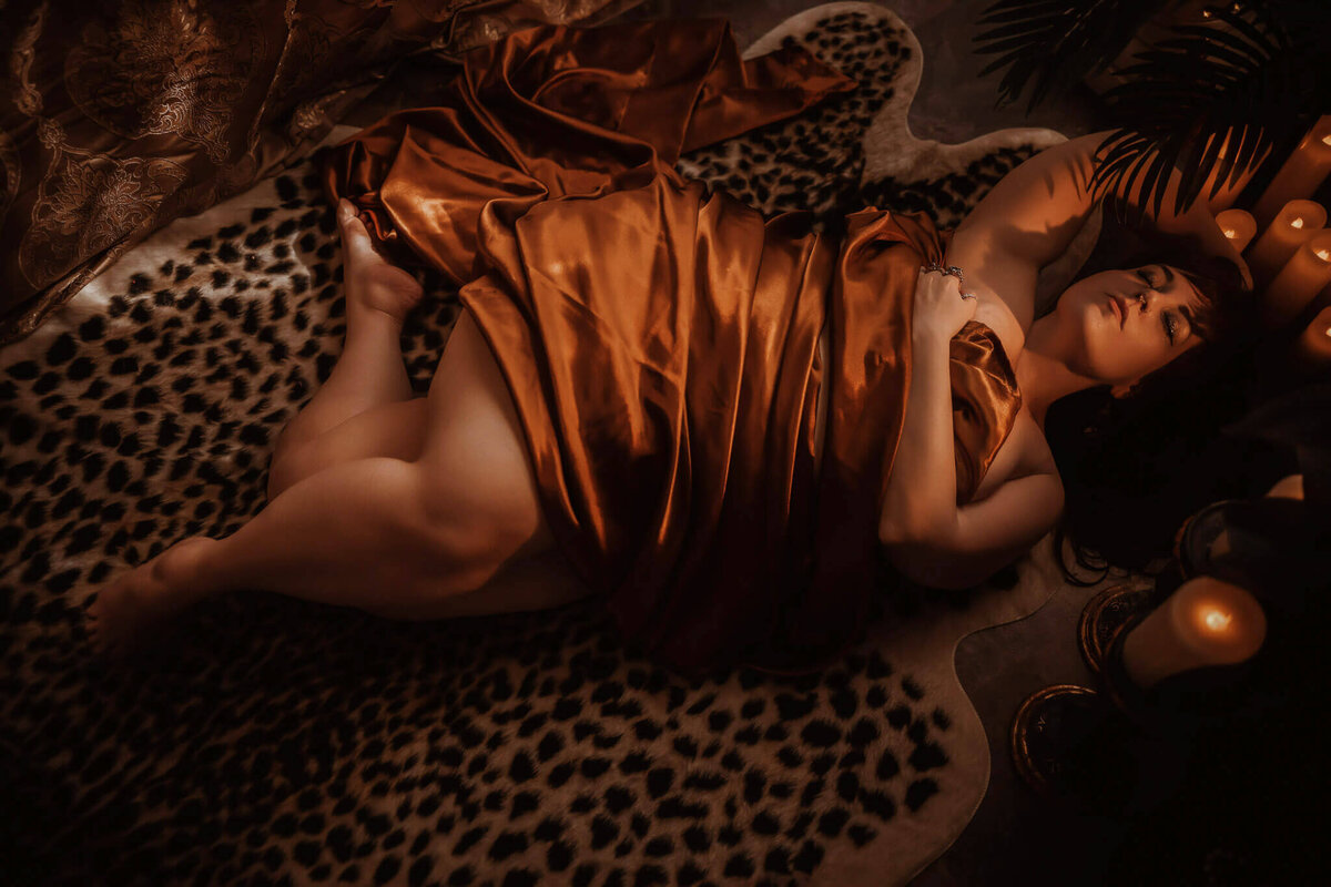 Woman in copper sheets lying on a leopard rug in a  boudoir studio near Fort Worth