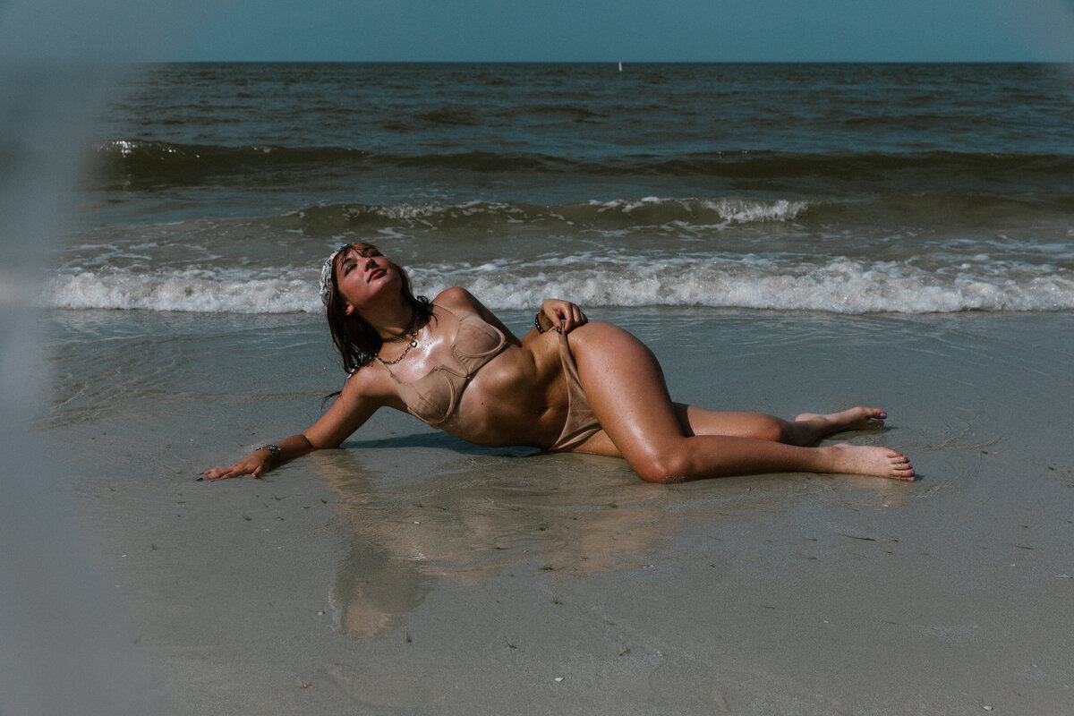 woman laying on fort myers beach with the waves crashing behind her
