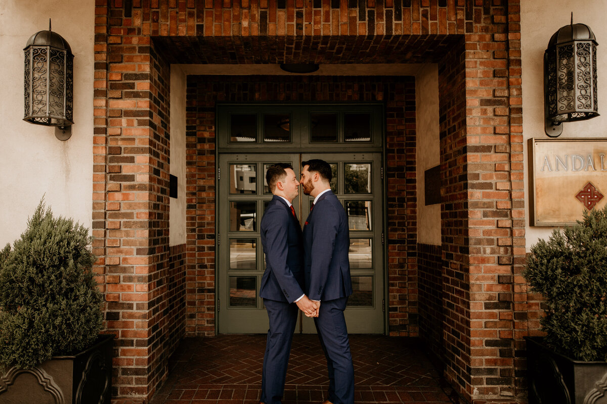same sex couple standing in front of a brick building in downtown Albuquerque