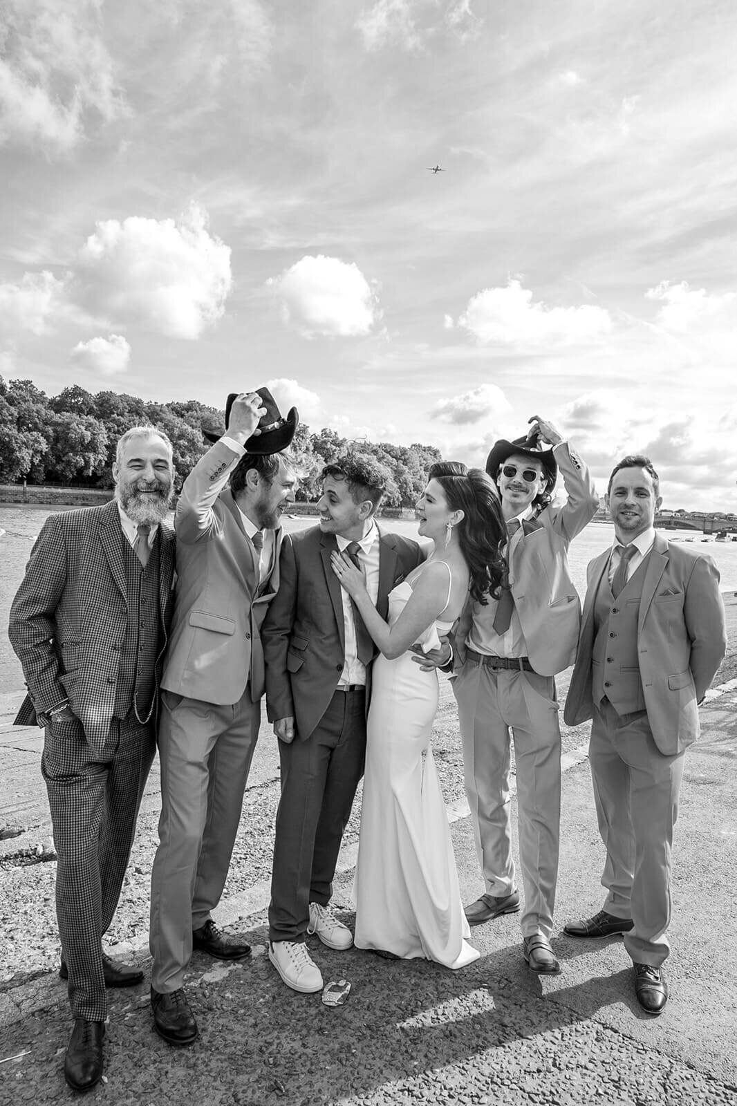 Bride and groom posing with cowboys on Putney riverbank