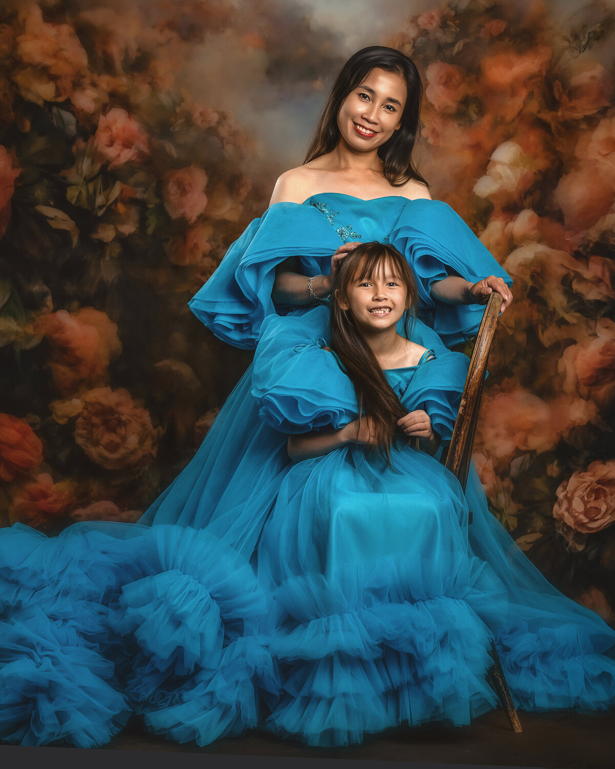 Talk about mother-daughter goals! These two are absolutely stunning in their matching turquoise ball gowns against our signature floral backdrop. There's nothing quite like capturing that special bond between mama and her mini-me—these are the moments you'll want to treasure forever.