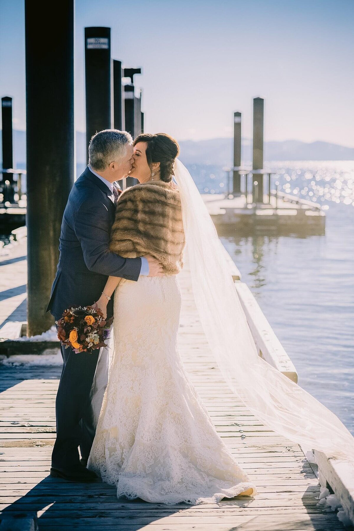 bride and groom on the Hyatt Tahoe pier during a winter wedidng bride wearing grandma furr