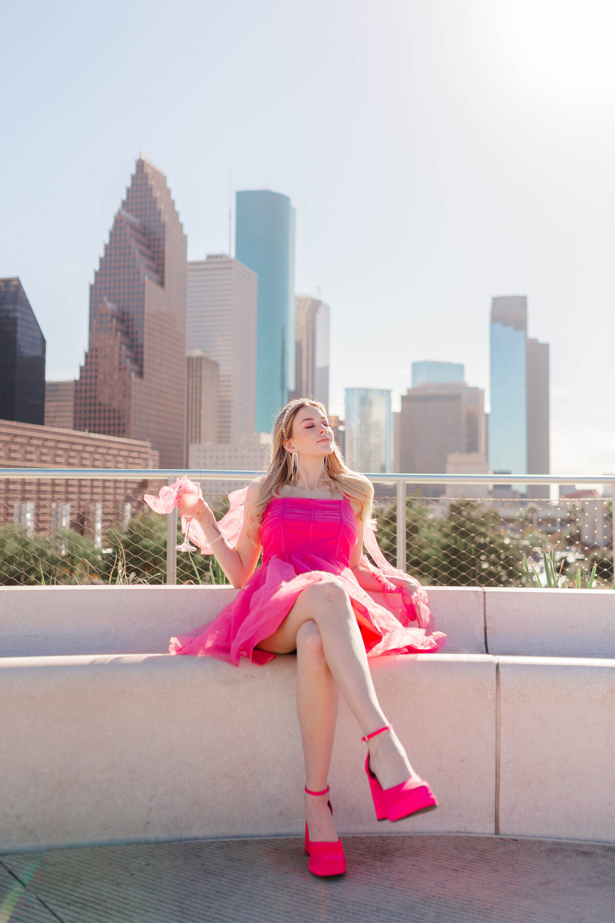 barbie model sitting on rooftop in front of downtown houston skyline