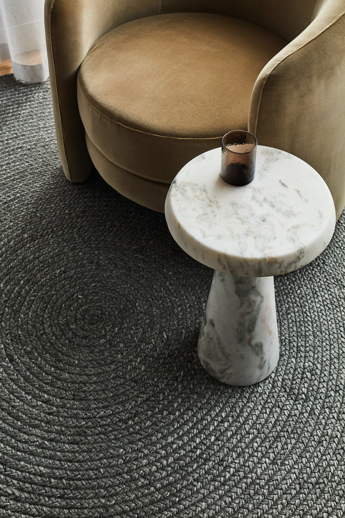 Melbourne interior design detail with marble side table, velvet armchair, and textured rug.