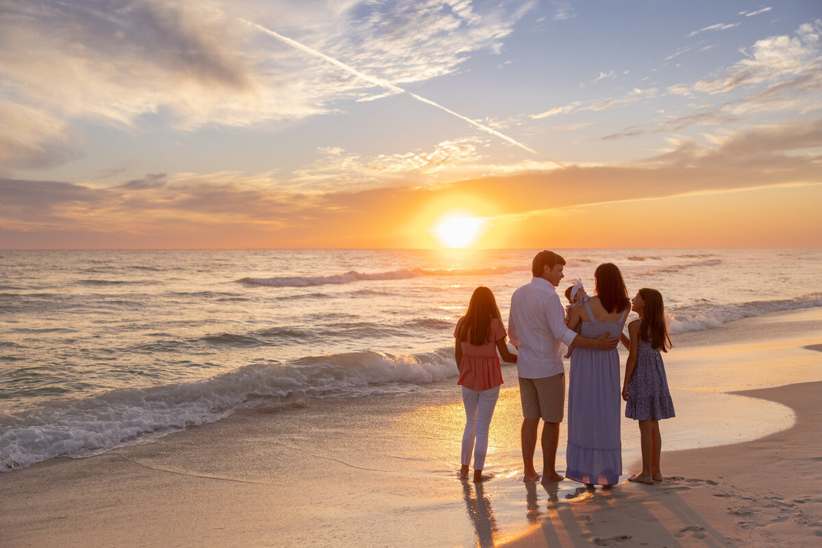 A family walking along the shore at sunset in Rosemary Beach for an artistic family portrait.