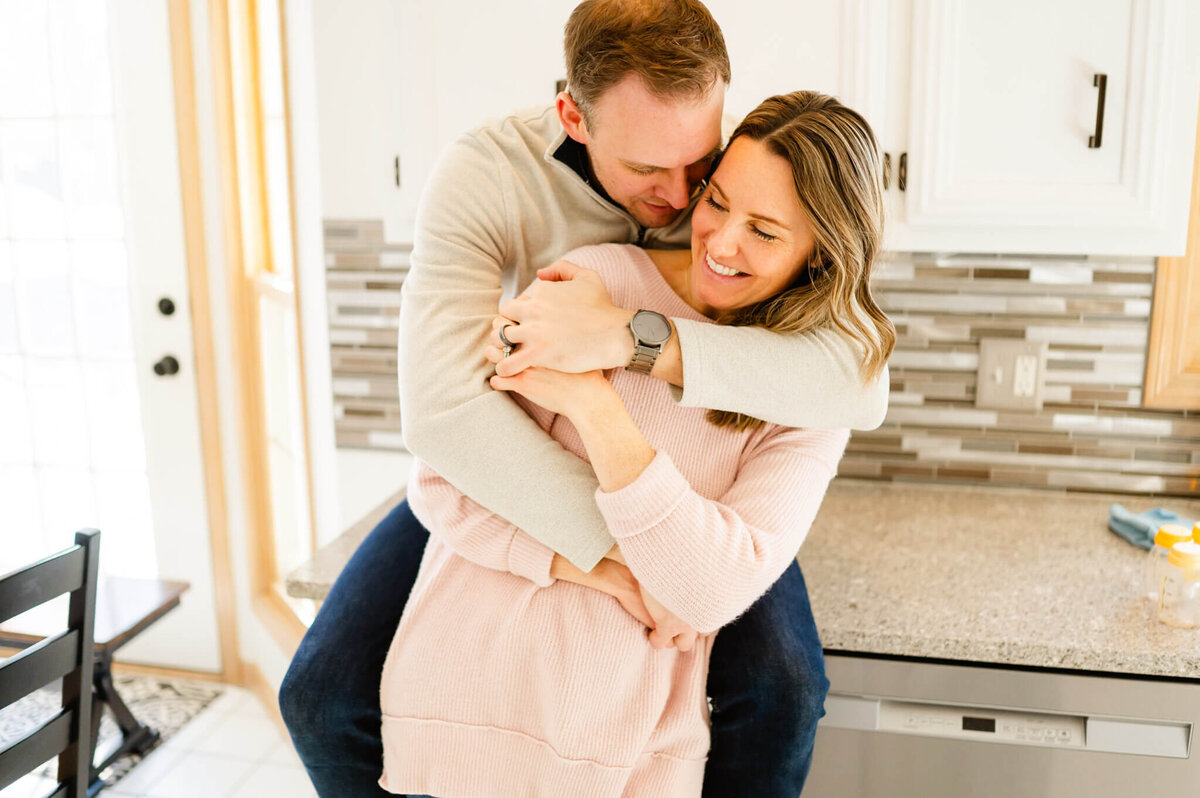 Couple embracing by kitchen counter at an in home photography session by Everything is Grace.
