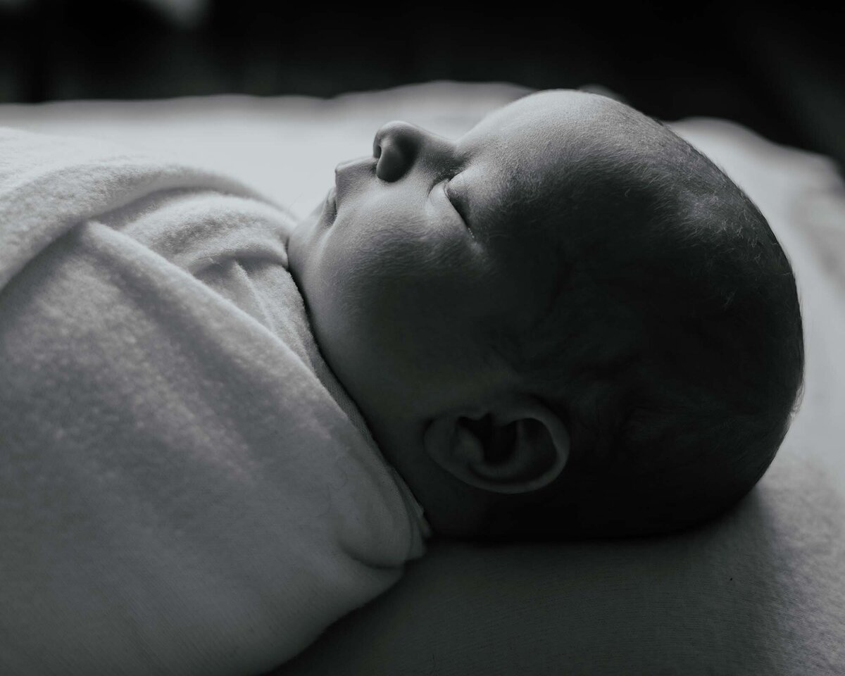 Maddie Rae Photography black and white side profile of sleeping baby all swaddled up.