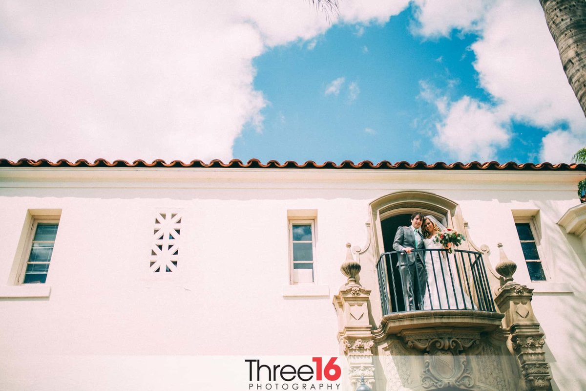 Bride and Groom stand on a small balcony overlooking their guests at the Muckenthaler Mansion in Fullerton