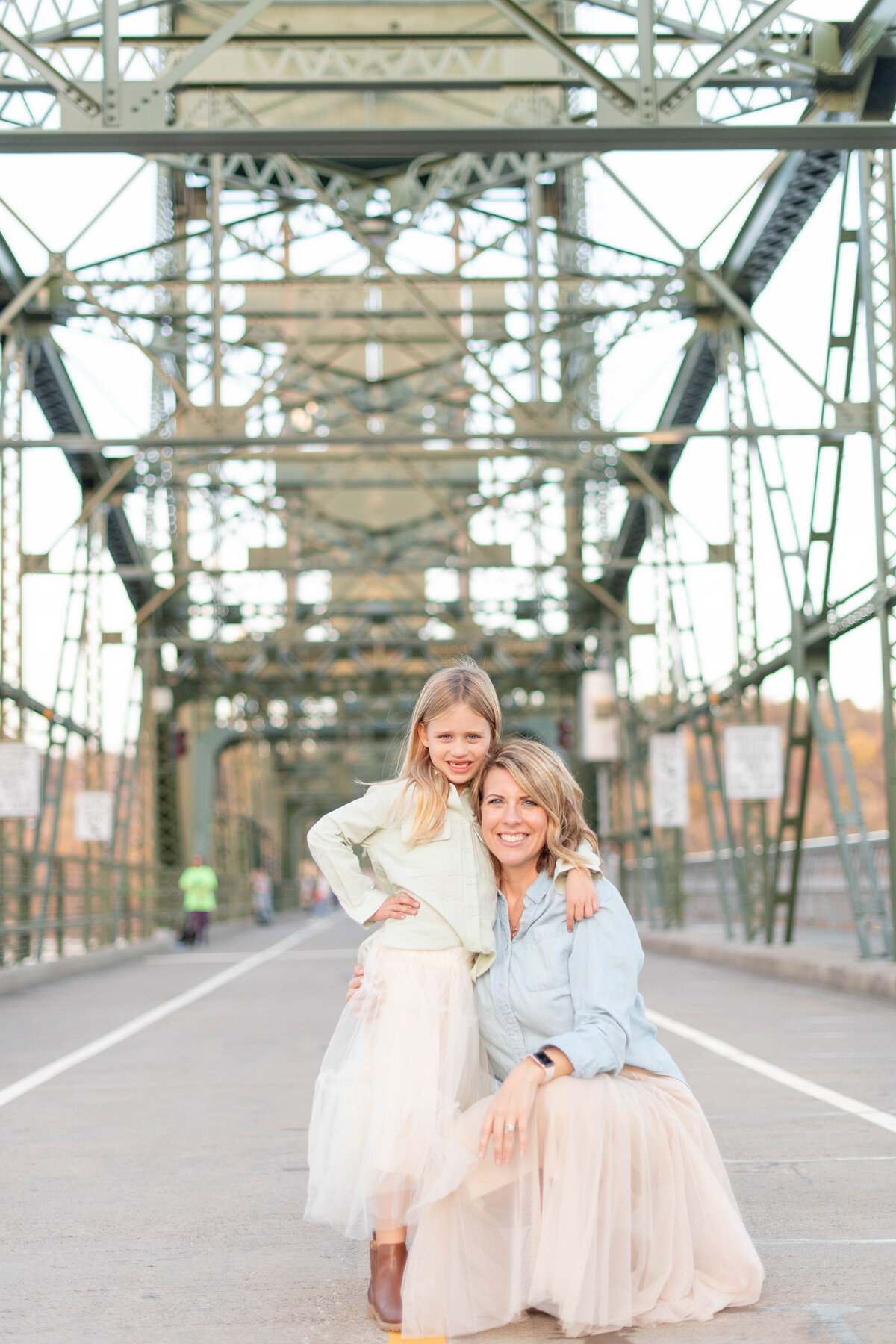 mother and daughter posing on bridge