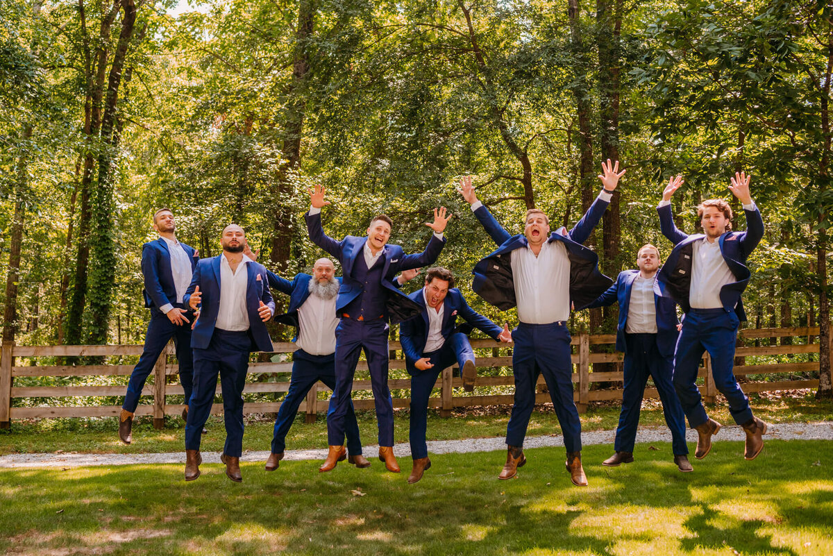 Photo of men and navy suit jumping and cheering in the woods