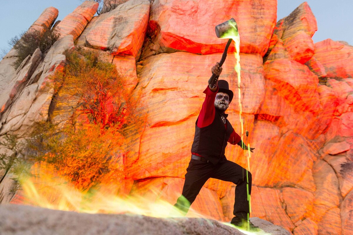 A man pours green fire on a rock with canyon wall behind as a part of entertainment at an incentive travel event