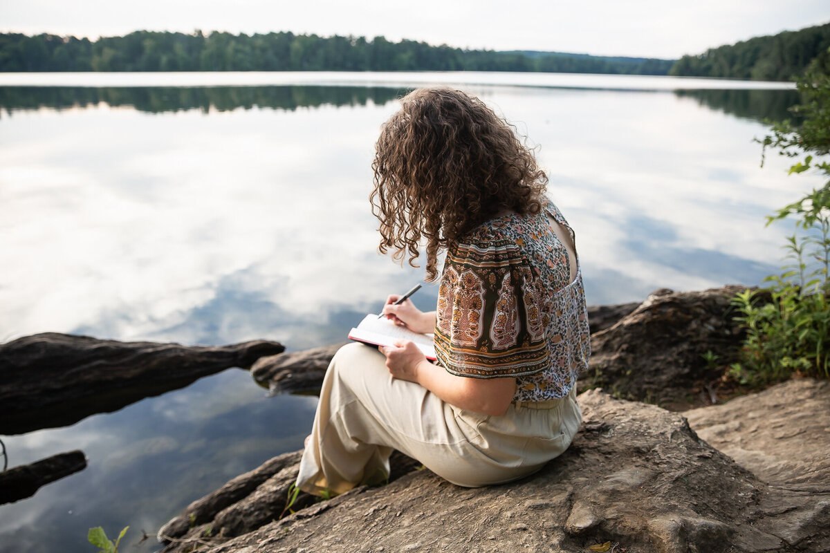 An author writes by a beautiful lake in Baltimore, Maryland during branding photos.