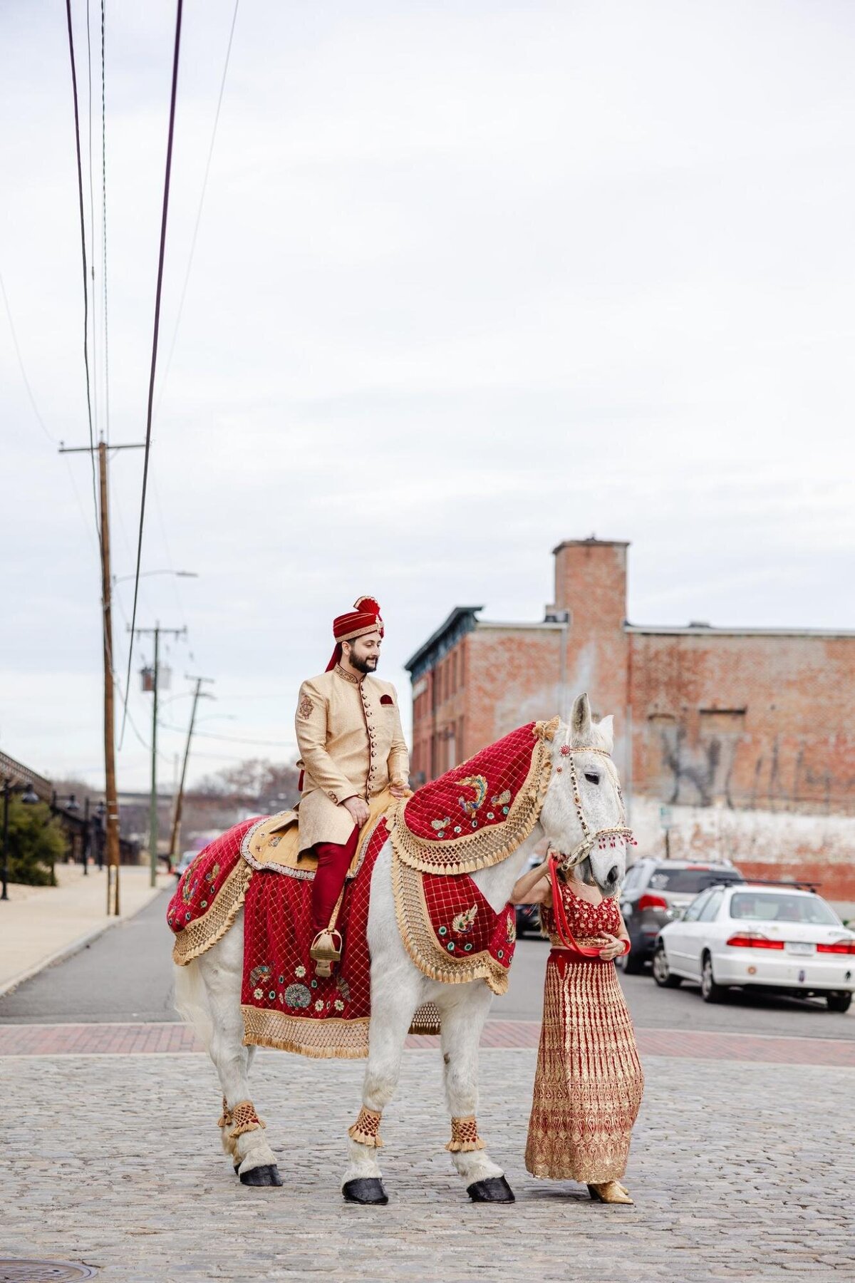 Man in traditional attire riding a decorated horse on an urban street.